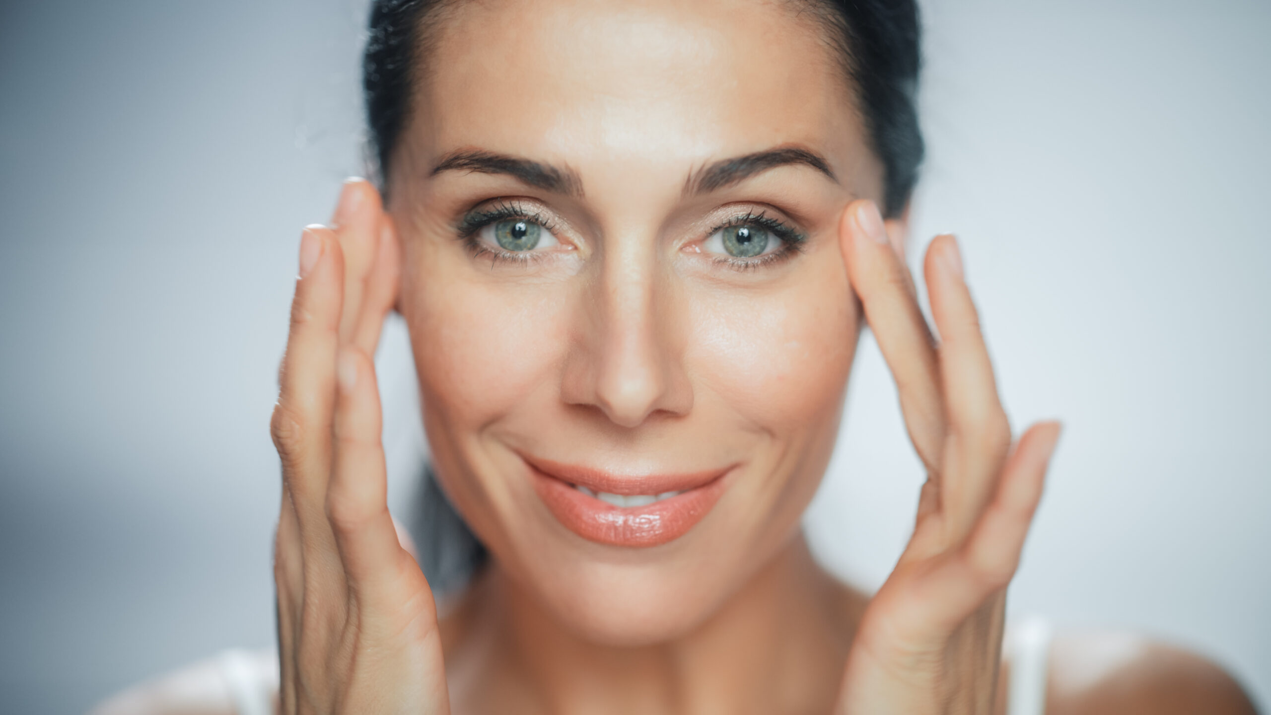 Beautiful caucasian woman touching her wrinkle-free skin on her face