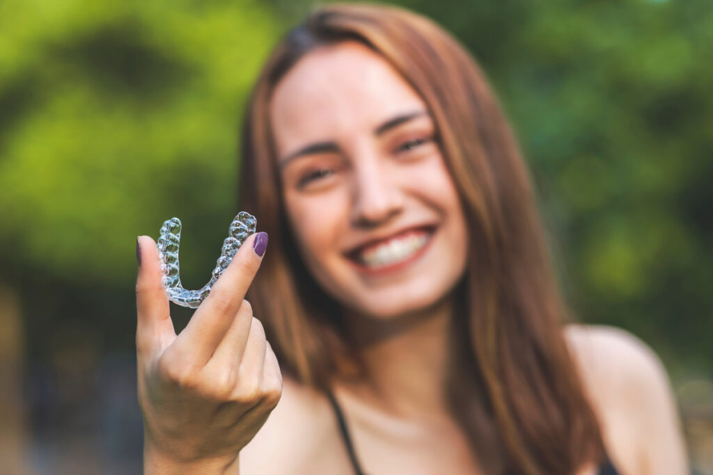 Beautiful smiling Turkish woman is holding an invisalign bracer
