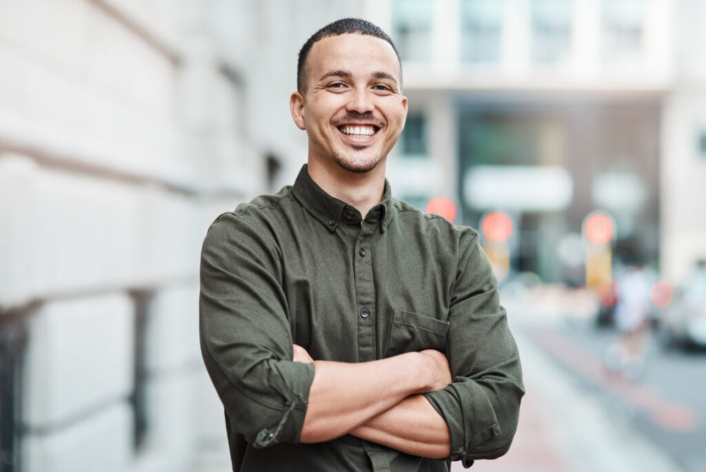 Business man standing with arms crossed, looking confident and proud in the city alone. Portrait of a black male entrepreneur or worker showing vision, ambition and success with arms folded downtown.