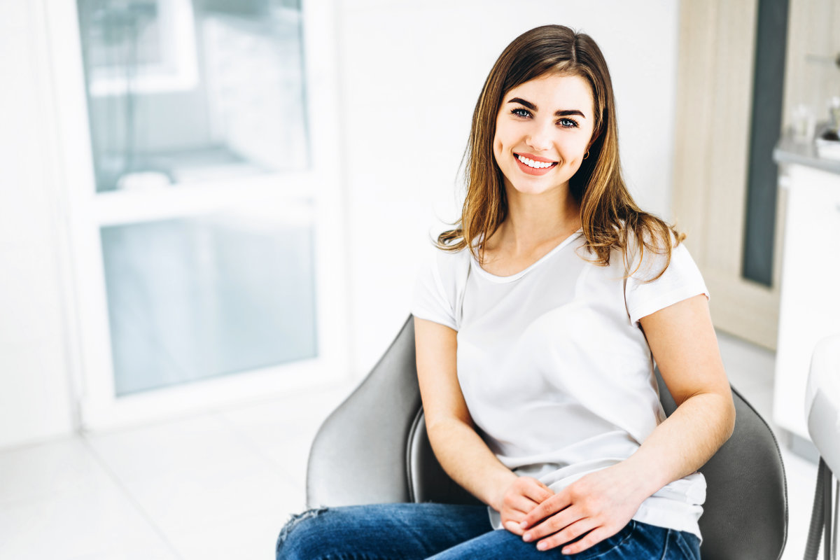 Pretty happy and smiling dental patient sitting in the dental chair at the dental office