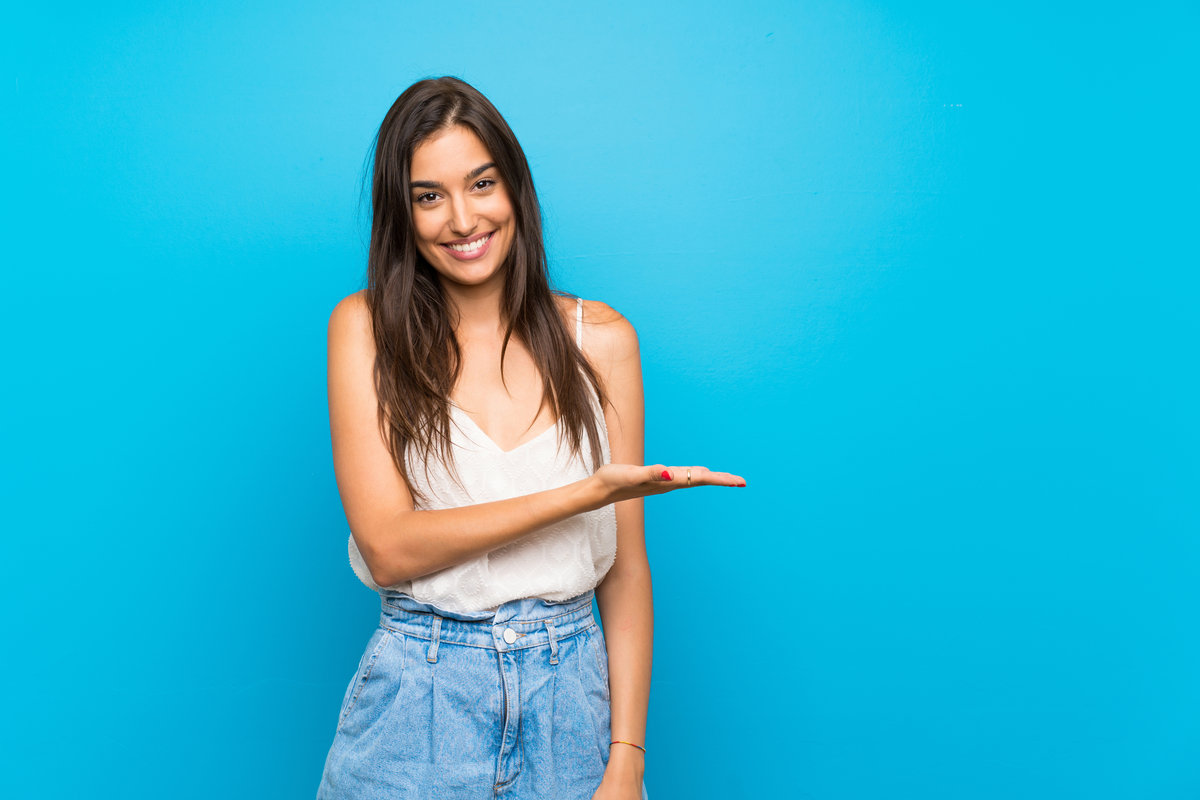 Young woman over isolated blue background smiling with a happy and pleasant expression
