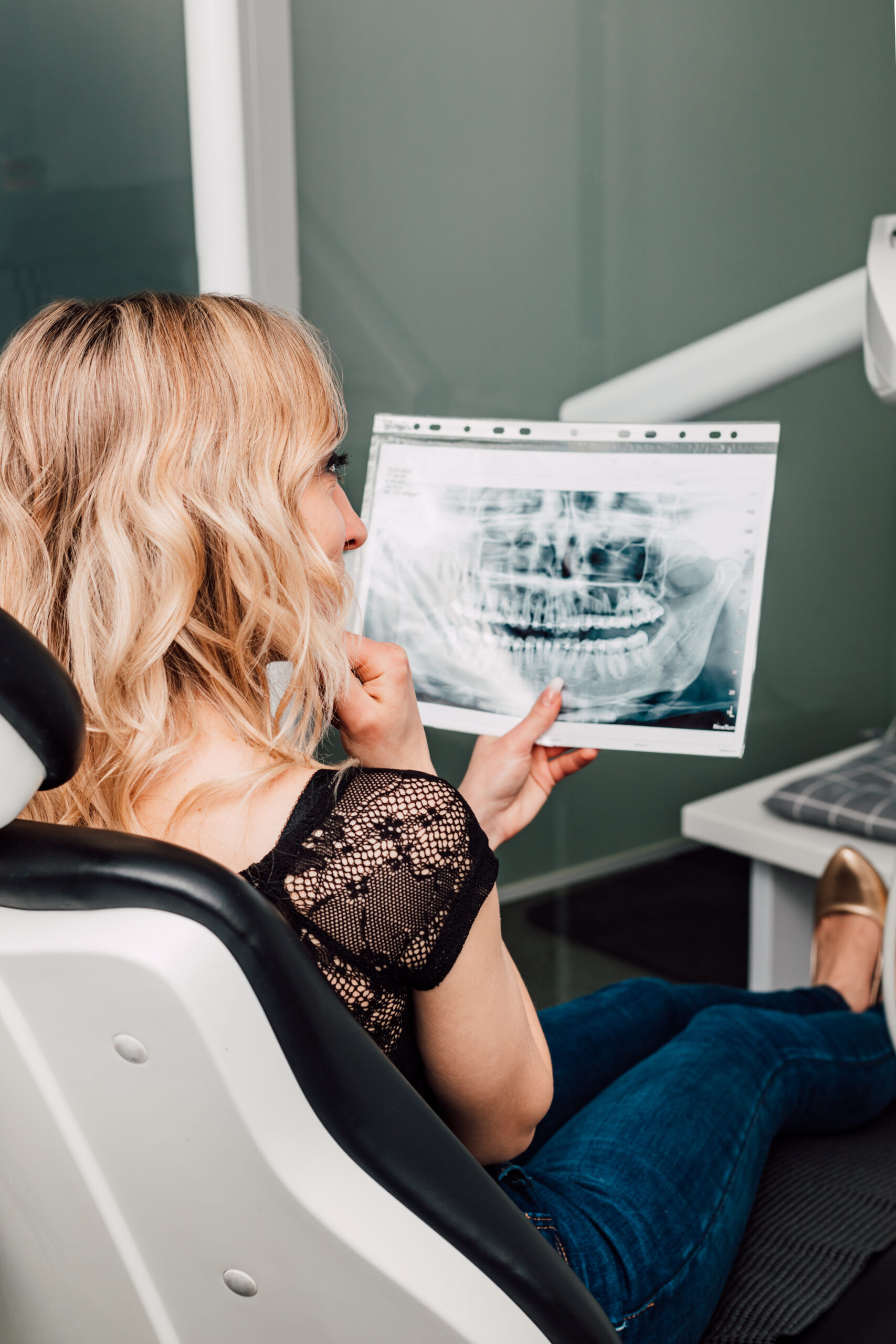 A woman in a dental chair looks at an X-ray of her teeth. High quality photo